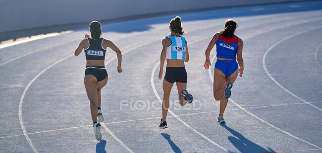 Female track and field athletes running in competition on track — Stock Photo