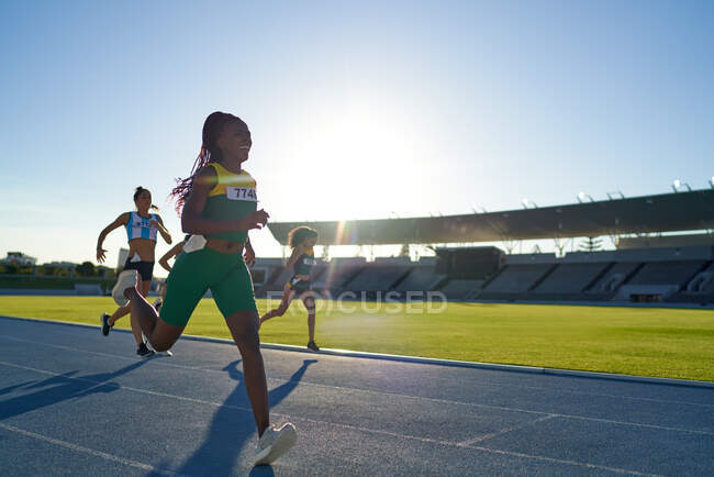 Happy female track and field athlete winning ace on sunny track — Stock Photo