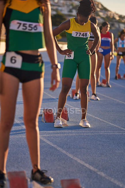 Female track and field athletes preparing at starting blocks — Stock Photo
