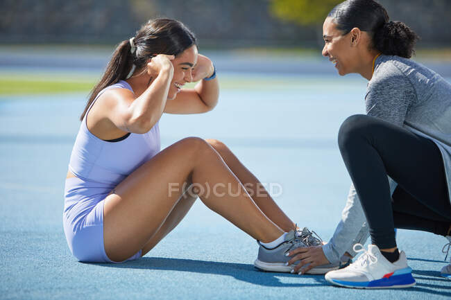 Feliz pista feminina e atletas de campo fazendo sit ups na pista — Fotografia de Stock