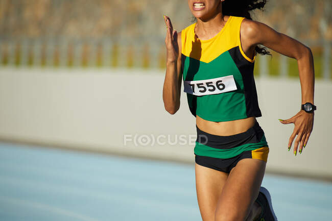 Determined female track and field athlete running in competition — Stock Photo