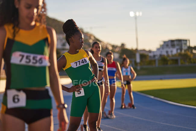 Atletas de atletismo do sexo feminino se preparando em blocos iniciais na pista — Fotografia de Stock