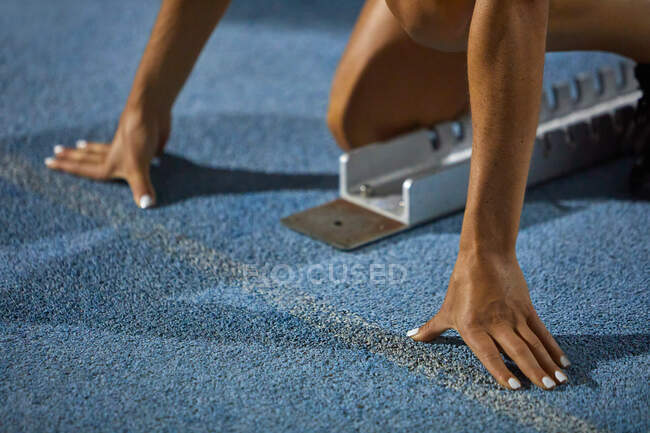 Close up female track and field athlete at starting block — Stock Photo
