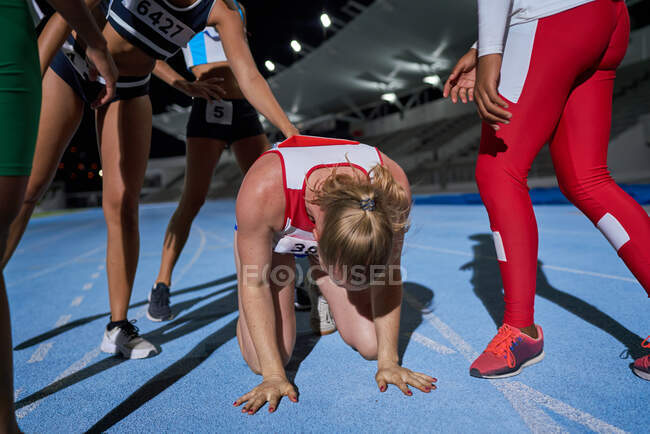 Atletas de atletismo do sexo feminino apoiam corredora cansada na pista — Fotografia de Stock