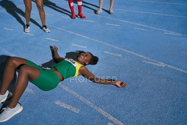 Pista cansada y atleta de campo acostado en pista soleada - foto de stock