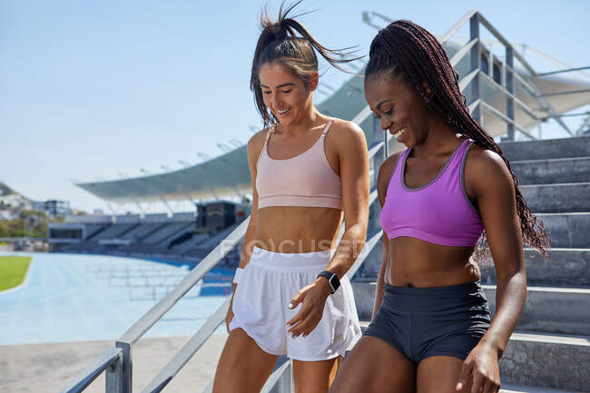 Female track and field athletes descending steps in sunny stadium — Stock Photo