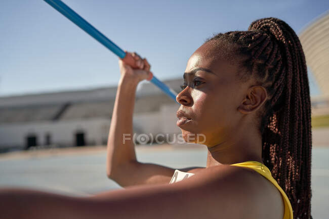 Close up determined female track and field athlete throwing javelin — Stock Photo