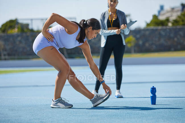 Female track and field athlete stretching — Stock Photo