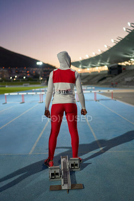Hembra atleta de pista y campo en hijab en el bloque de partida en pista - foto de stock