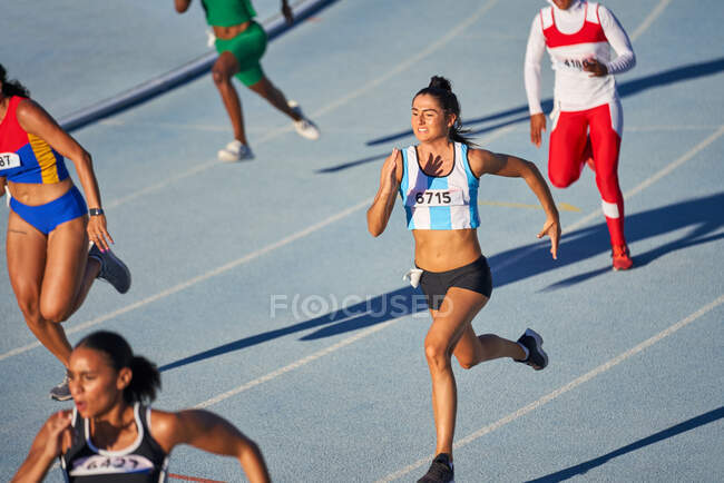 Atletas de atletismo do sexo feminino competindo em pista ensolarada — Fotografia de Stock