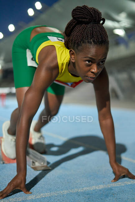 Determined track and field athlete at starting block on track — Stock Photo