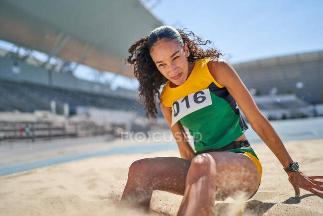 Female track and field athlete long jumping in sand — Stock Photo