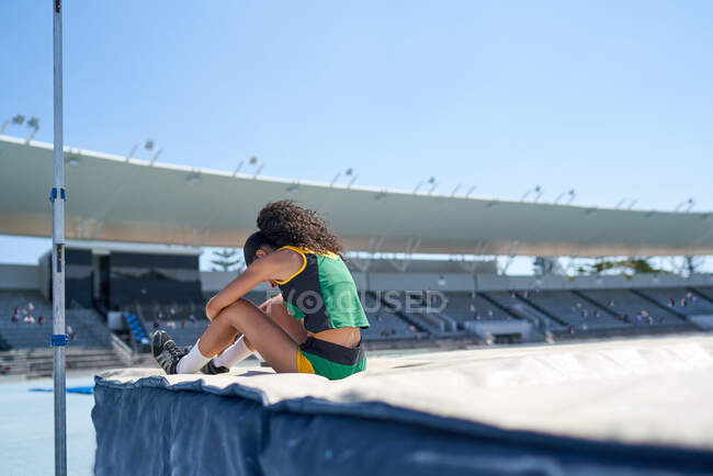 Fêmea faixa e campo saltador em altura no estádio ensolarado — Fotografia de Stock
