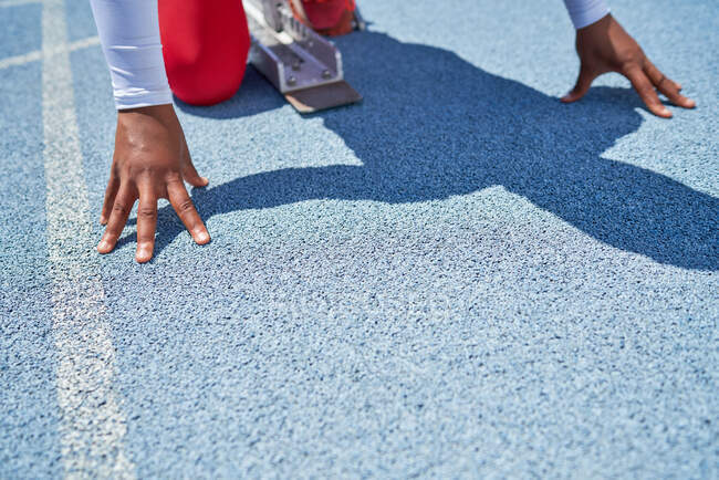 Close up hands of female track and field athlete at starting block — Stock Photo