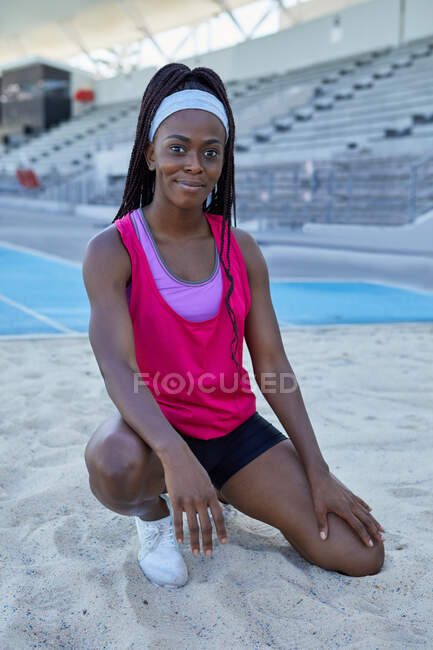 Portrait confident female track and field athlete in long jump sand — Stock Photo