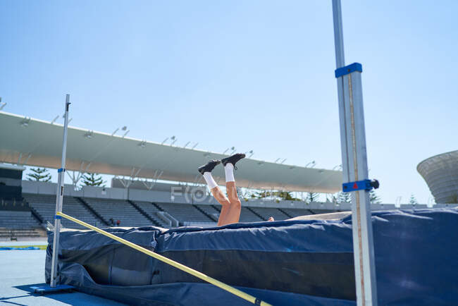 Athlète féminine d'athlétisme tombant sur le saut en hauteur — Photo de stock