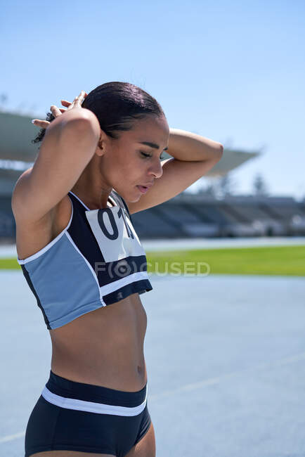 Deportista de pista y campo femenino determinado en pista soleada - foto de stock