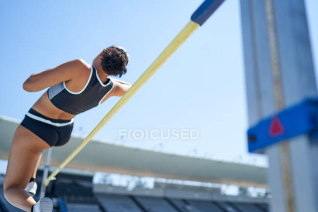 Female track and field athlete high jumping — Stock Photo