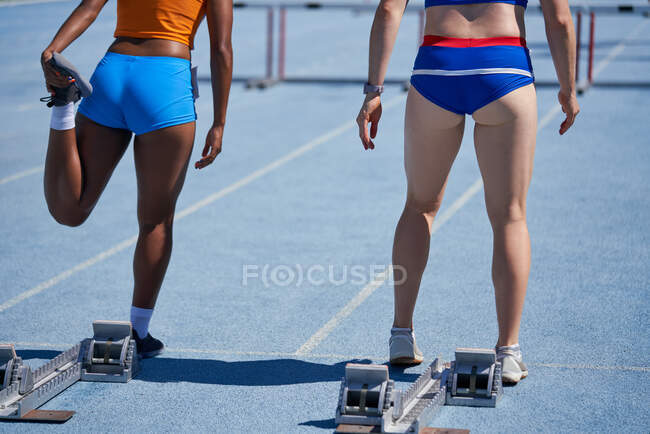 Female track and field athletes preparing at starting blocks — Stock Photo