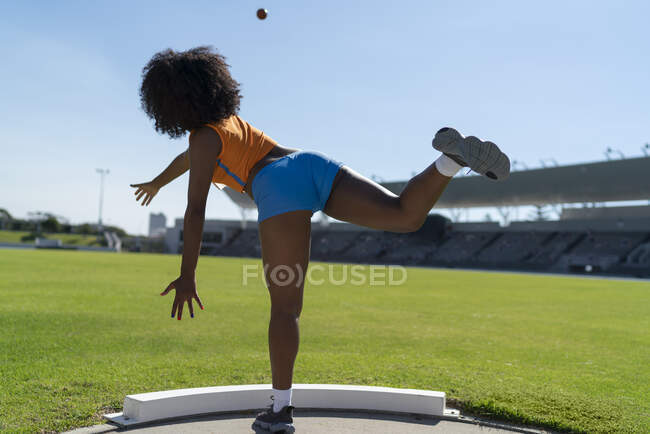 Pista femminile e atleta campo tiro colpo messo in soleggiato infield — Foto stock