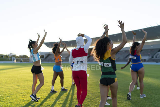 Track and field athletes waving to audience in stadium infield — Stock Photo