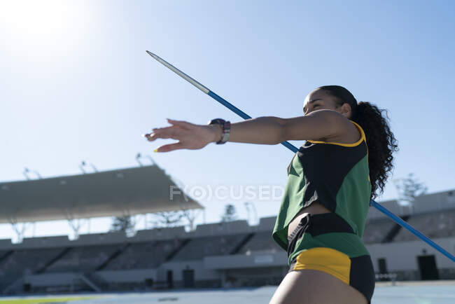 Сосредоточенная легкоатлетка бросает копье на стадионе — стоковое фото