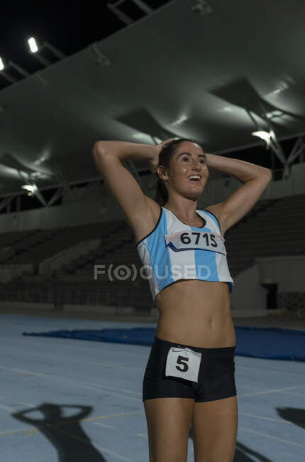 Happy female track and field runner finishing race on sports track — Stock Photo
