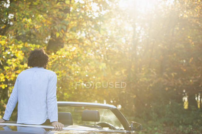 Jovem no conversível relaxante apreciando ensolarado outono parque árvores — Fotografia de Stock