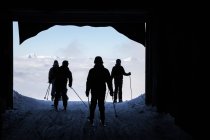 Hintere Silhouetten von Skifahrern, die Tunnel in den Bergen verlassen — Stockfoto