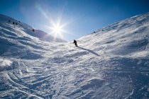 Vista de ángulo bajo de la persona de esquí en la ladera nevada de la montaña - foto de stock