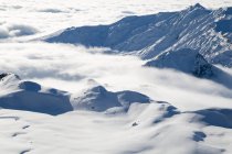Вид с воздуха на покрытые облаками горы и горнолыжную станцию в тумане — стоковое фото