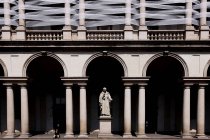 Милан, Палаццо Брера. Человек, сидящий возле колонн и статуи Джованни Антонио Лабуса — стоковое фото