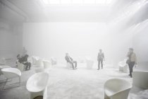 17 avril 2011. Milan, Salone del Mobile, Fuori Salone. Personnes dans une chambre éclairée avec des chaises blanches — Photo de stock