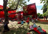 Le 24 juillet 2010. Londres, Hyde Park, Personnes se reposant près du pavillon de la galerie Serpentine rouge par Jean Nouvel — Photo de stock