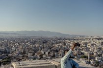 21 de julio de 2017. Grecia, Atenas, Acrópolis. Hombre tomando fotos con paisaje urbano - foto de stock