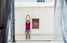 3 августа 2017 года. Греция, Парос, Продромос. Женщина растягивается рядом со зданием — стоковое фото