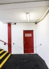Saída de emergência porta vermelha e escadas no edifício — Fotografia de Stock