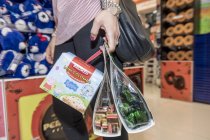 13 avril 2017. Italie, Milan. Vue recadrée de la femme portant des sacs avec des bonbons en magasin — Photo de stock