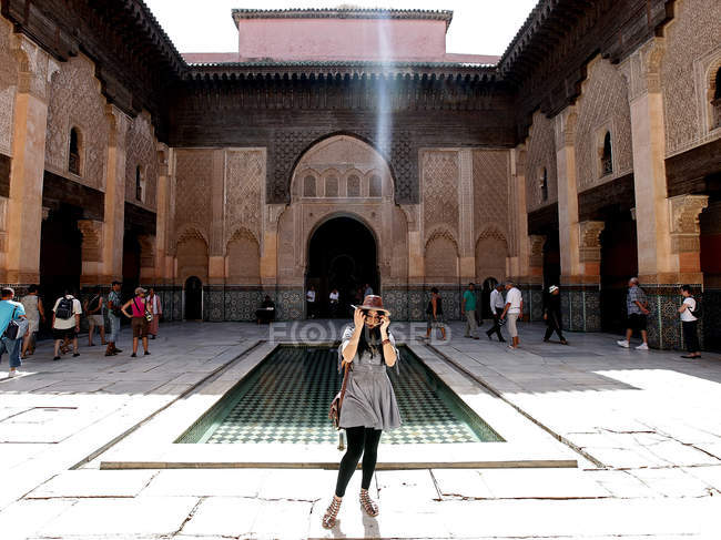 30 de septiembre de 2010. Marruecos, Marrakech, Medersa Ben Youssef. Mujer poniéndose gafas de sol cerca de la piscina - foto de stock