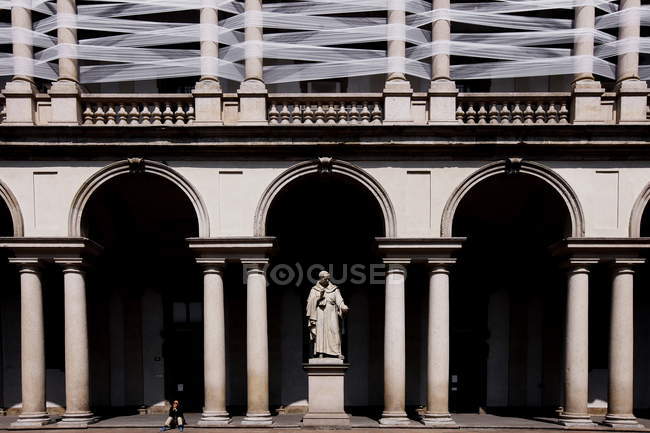 Milan, Palazzo Brera. Person sitting near columns and statue of Giovanni Antonio Labus — Stock Photo