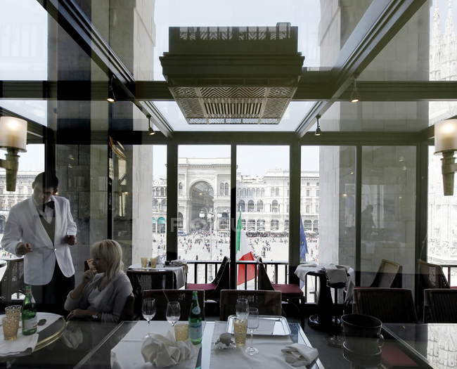 3 мая 2011 года. Милан, Пьяцца дель Дуомо. Палаццо дель Аренгарио. Официант и женщина в ресторане с видом на площадь — стоковое фото
