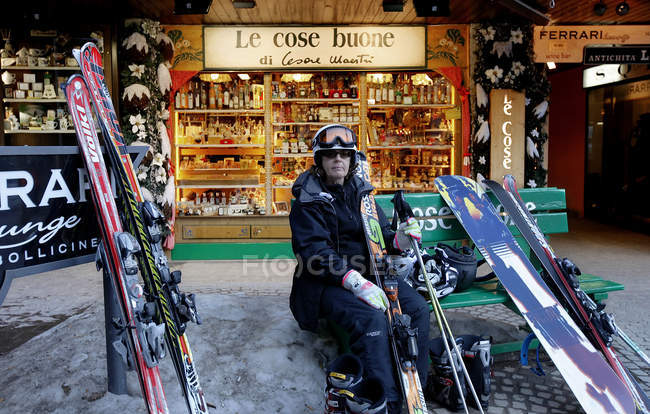 14. märz 2010. italien, madonna di campiglio, porträt einer skifahrerin, die mit skiausrüstung auf einer bank sitzt — Stockfoto