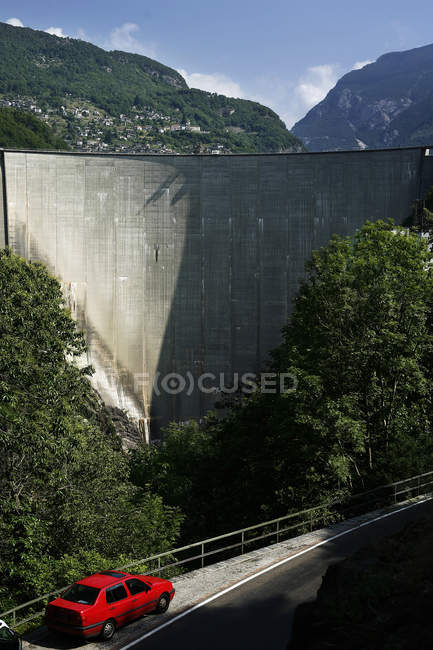 Switzerland, Verzasca valley. Red car parked near Lago di Vogorno dam — Stock Photo