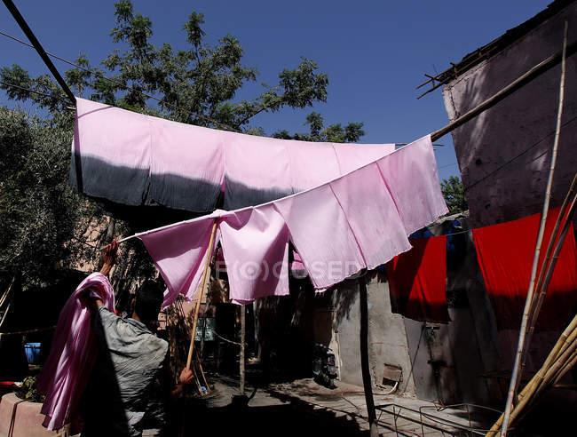 Ritratto posteriore dell'uomo che prende pezzi di tessuto rosa dal bastone, Marocco, Marrakech — Foto stock