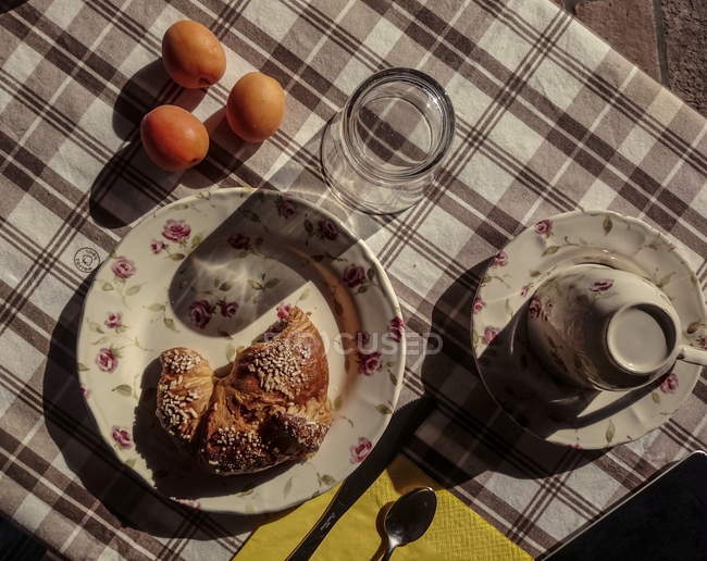 Вид сверху на круассан с яйцами и посудой на клетчатой скатерти — стоковое фото
