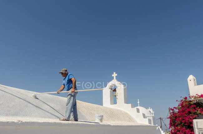 24 de julio de 2017. Grecia, Amorgos, Chora. Vista diurna del hombre pintando el techo de la iglesia - foto de stock