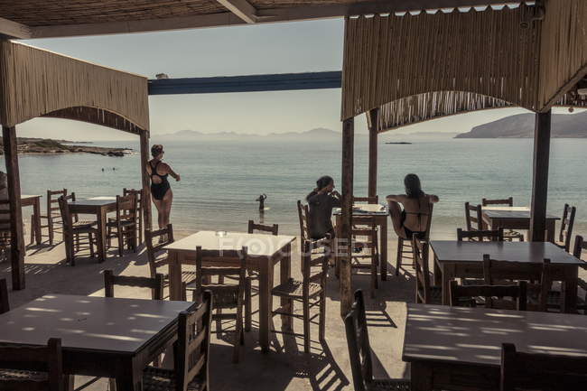28 de julio de 2017. Grecia. Retrato trasero de las mujeres en la cafetería junto al mar - foto de stock