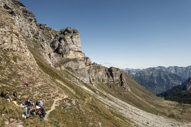 3 de septiembre de 2017. Italia, Alpe Devero. Grupo de excursionistas descansando en ladera de montaña - foto de stock