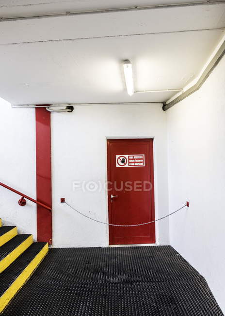 Salida de emergencia puerta roja y escaleras en el edificio - foto de stock