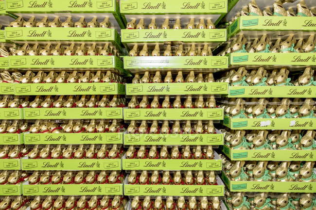 13 de abril de 2017. Italia, Milán. Muchos conejitos dulces envueltos en papel de aluminio en los estantes de las tiendas para la Pascua - foto de stock